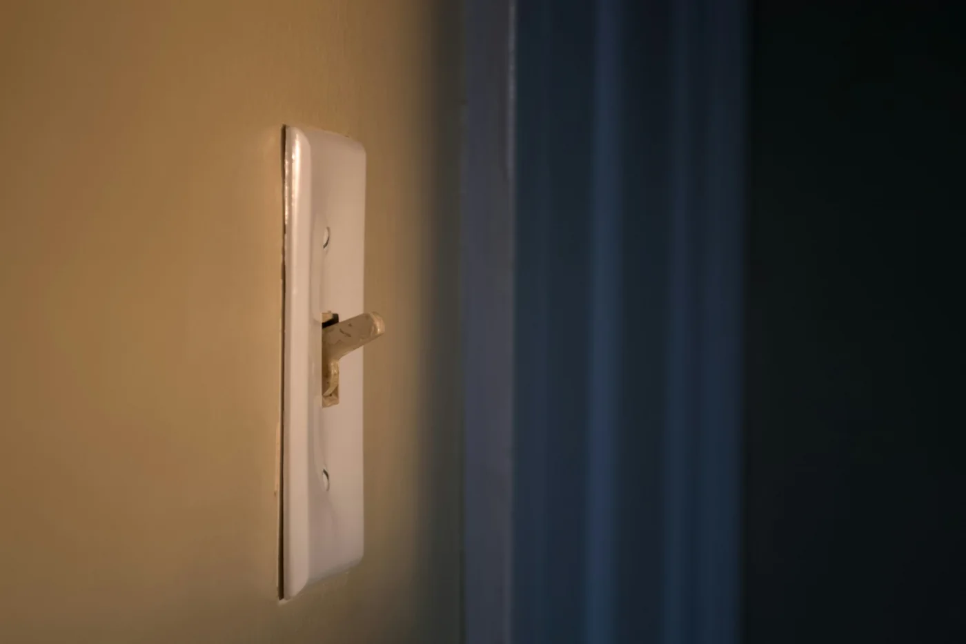A standard toggle light switch on an interior wall beside a door frame.