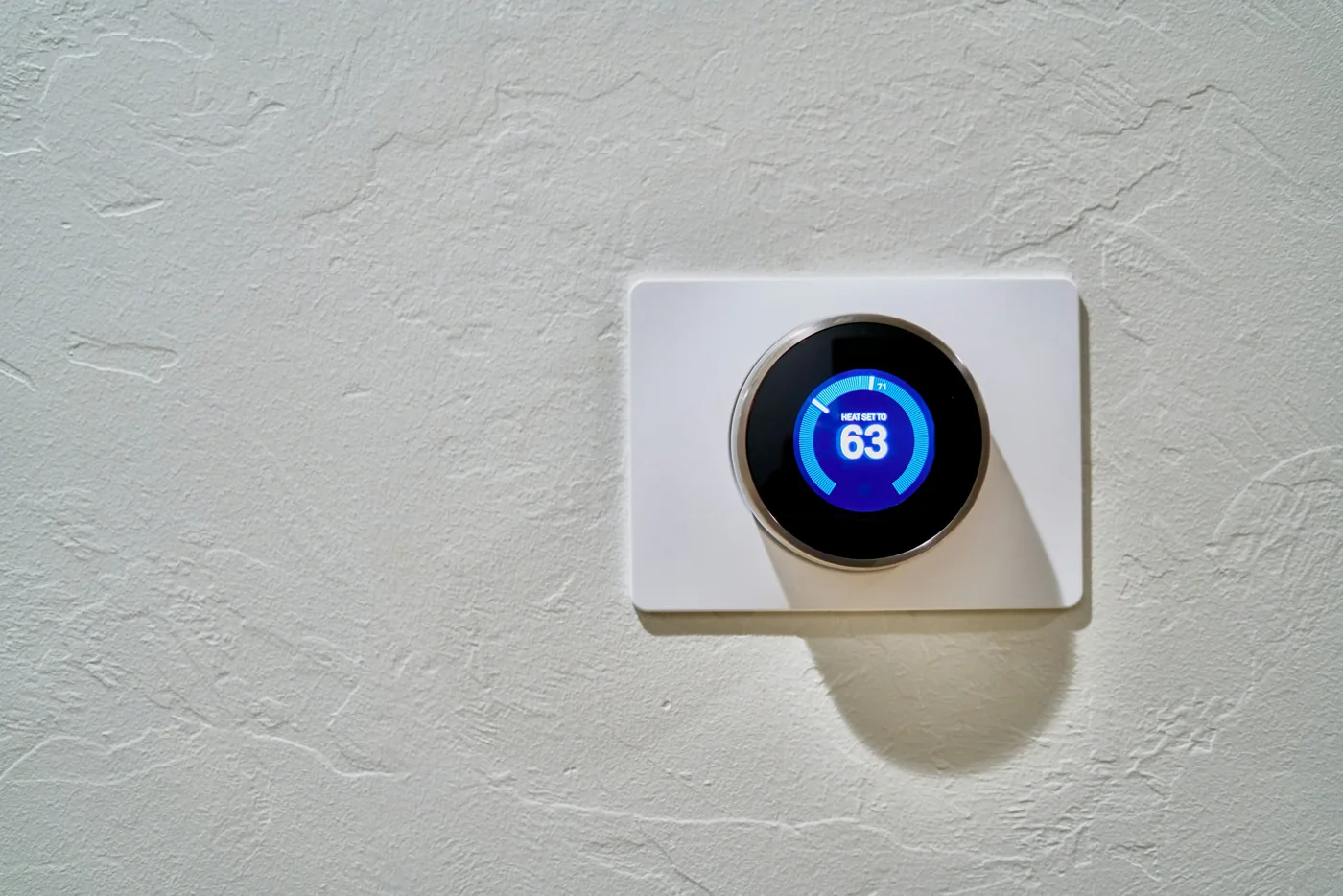 A round smart thermostat displaying a heating setpoint